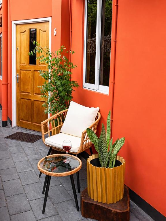 an orange wall with a chair and a plant at DOLFIJN STUDIOS Comfortable 1BR Apartment Fast WiFi AC North Paramaribo in Paramaribo