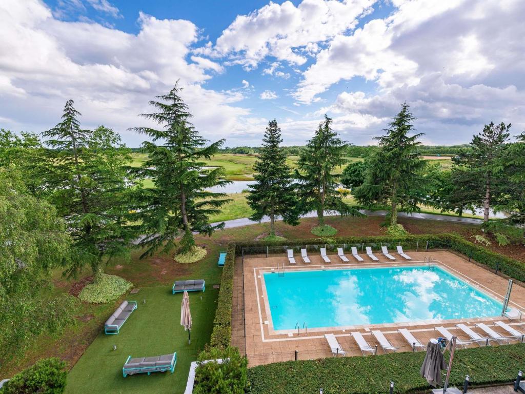 an overhead view of a pool with chairs and trees at Novotel Saint-Quentin en Yvelines in Magny-les-Hameaux