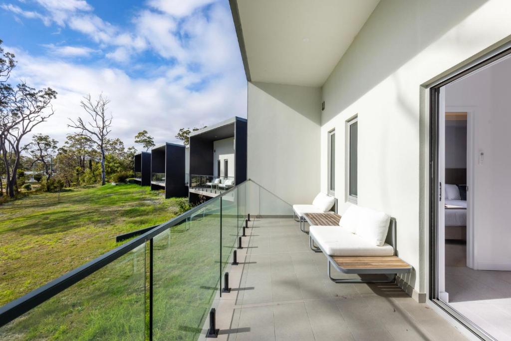 a glass balcony with a view of the yard at Modern 1 Bed Apartment - 6 Min Walk to Beach in Callala Beach