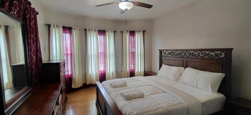a bedroom with a bed with a ceiling fan and windows at Eagle's Hub Niagara ny in Niagara Falls
