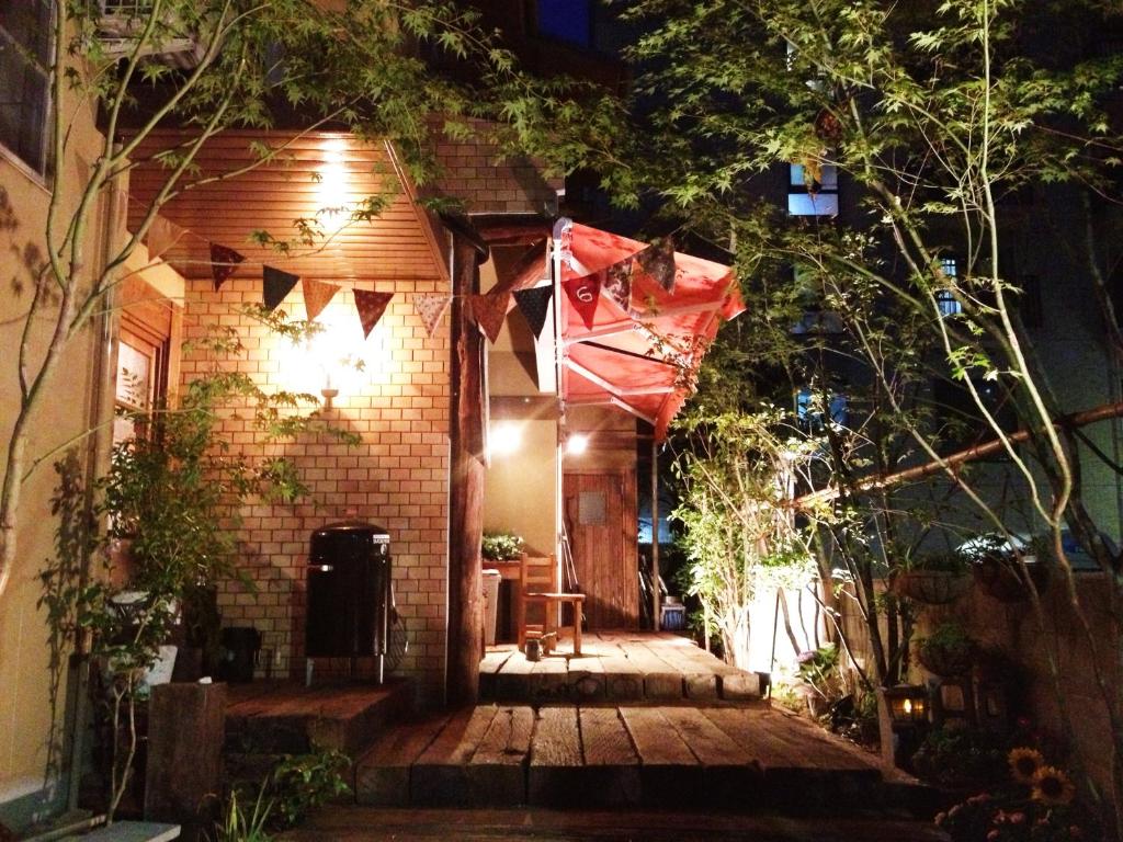 una pequeña casa con porche de madera por la noche en Roku Hostel Hiroshima en Hiroshima