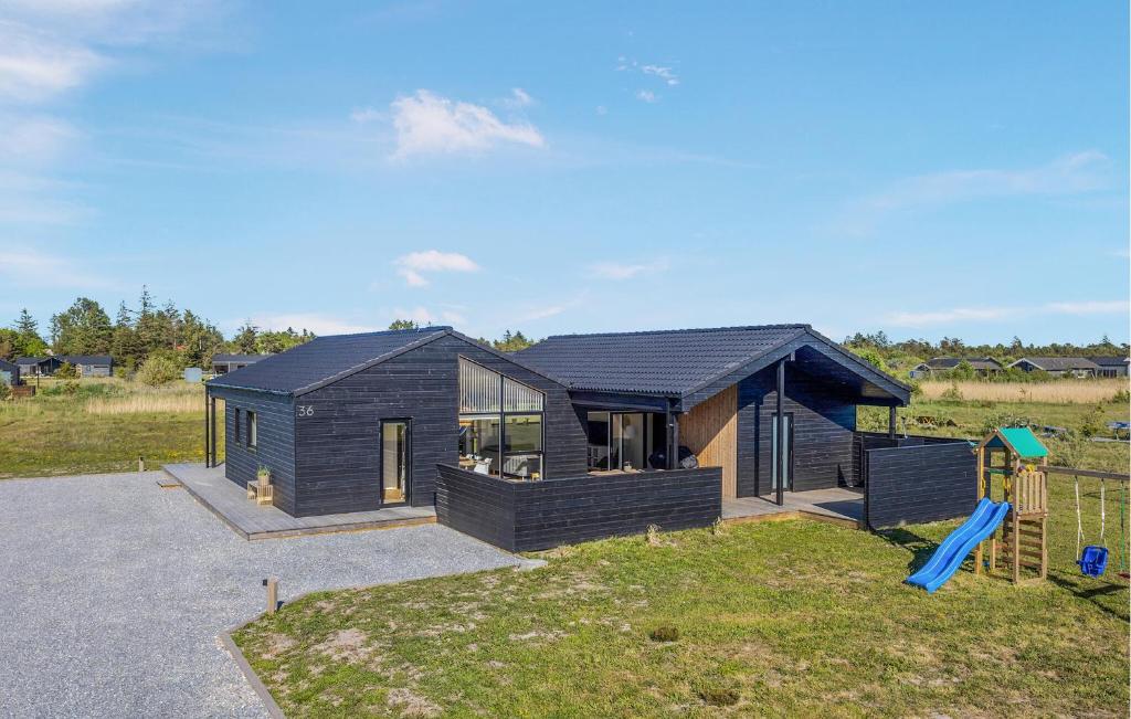 a black house with a playground in a field at Stunning Home In Jerup With Sauna in Jerup