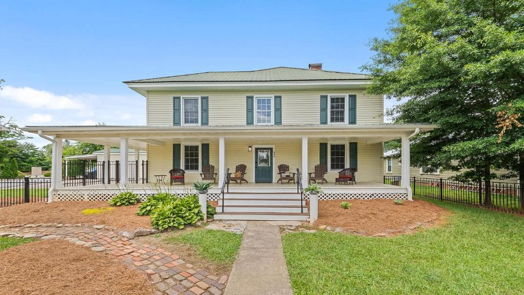 a yellow house with a porch and a fence at Brevard Bliss in Brevard