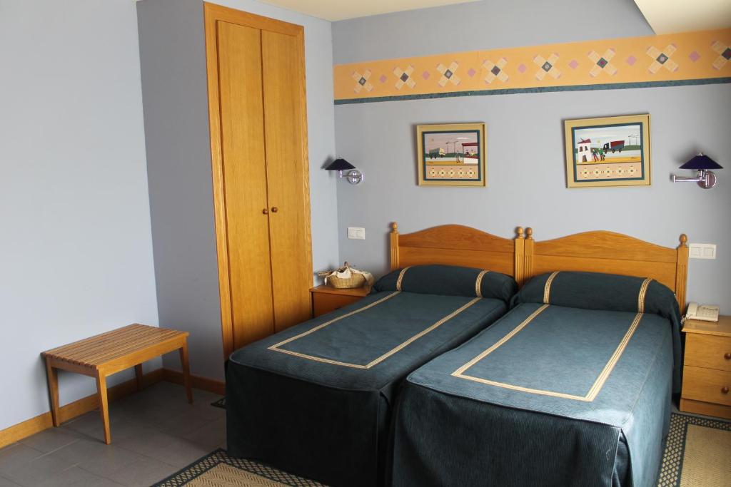 sypialnia z 2 łóżkami i drewnianym zagłówkiem w obiekcie Hostal Sandino w mieście Villodrigo