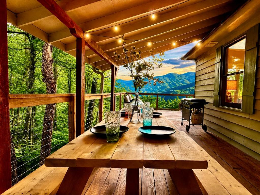 a wooden table on a porch with a view at Above the Clouds Cabin in Franklin