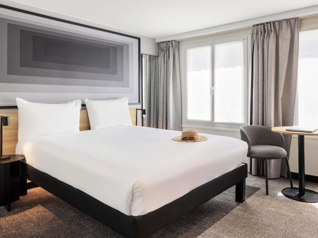 a hotel room with a large bed and a chair at ibis Paris Grands Boulevards Opéra 9e in Paris