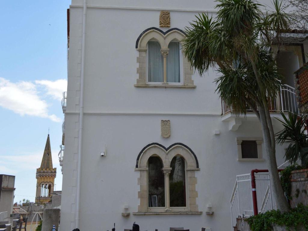a white building with a clock tower and a palm tree at Splendid Hotel Taormina in Taormina
