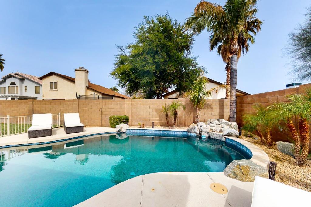 a swimming pool with two chairs and a palm tree at Suitewater in Peoria