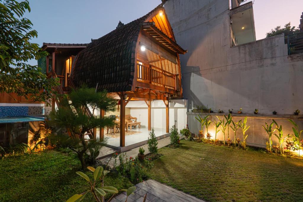 a house with a wooden roof and a yard at Villa Darma Ubud by Bali Cabin in Ubud