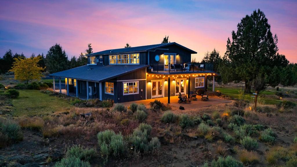 a large house with lights on in a field at Cascade Crest by AvantStay in Bend