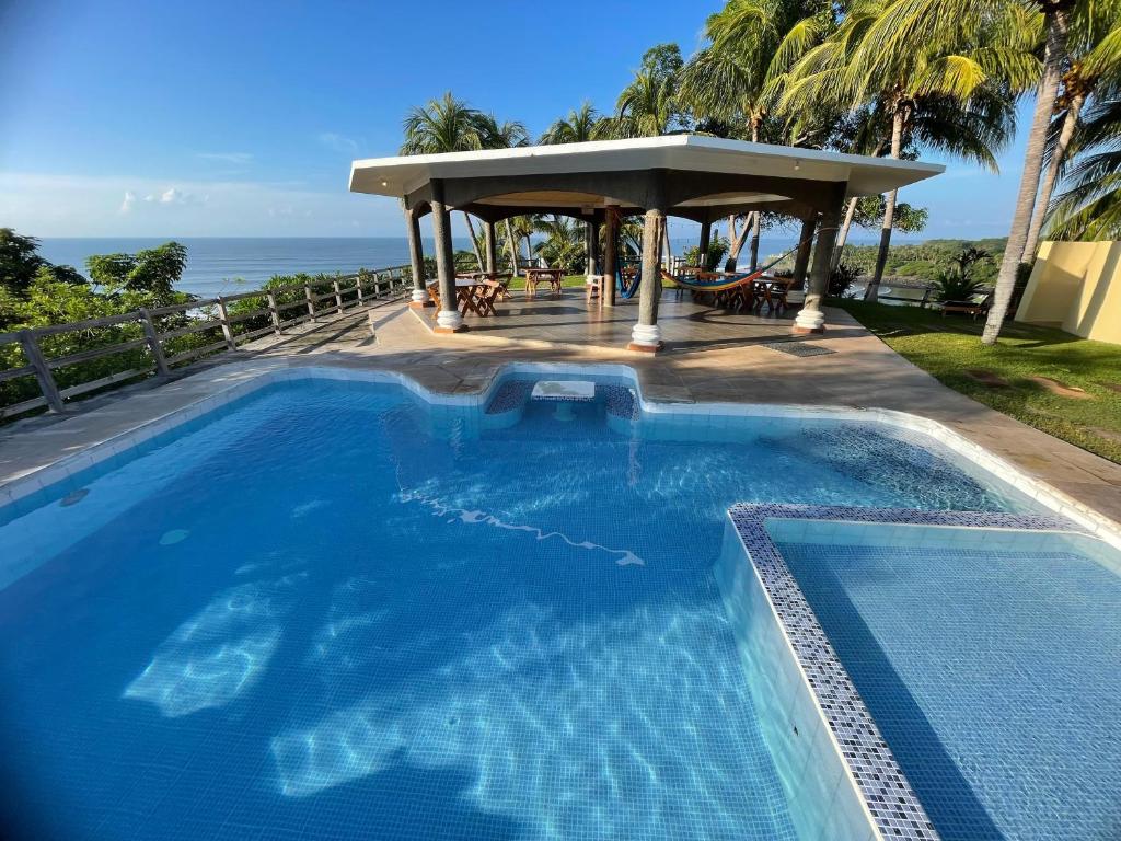 a swimming pool with a gazebo next to the ocean at Hotel Miraflores in El Cuco