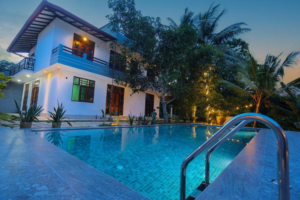 a swimming pool in front of a house at Blue Orchid Villa in Talpe