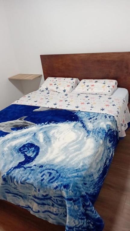 a bed with a blue and white blanket on it at Hotel Los alpes in Garagoa