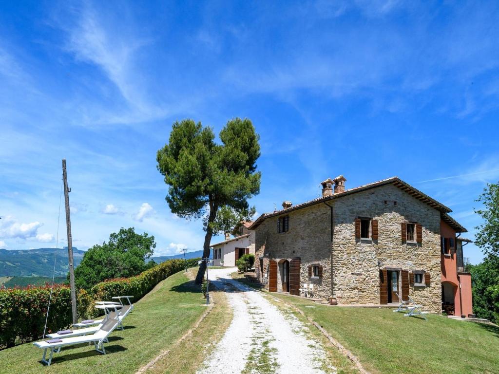an old stone house with a tree on a dirt road at Apartment in Sant'Angelo near Medieval Town in SantʼAngelo in Vado
