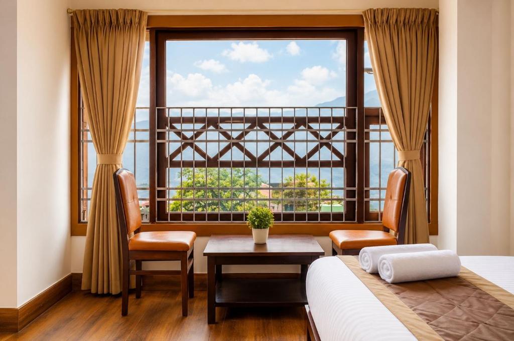 a bedroom with a large window and a bed and chairs at Gangtok Central Rooms in Gangtok