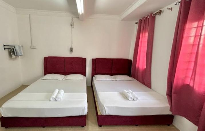 two beds in a small room with red curtains at 7Rooms Hotel Budget in Bandar  Pusat Jengka