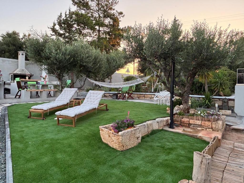 a backyard with green grass and two chairs and a hammock at Cretan stars villas Hersonissos in Hersonissos