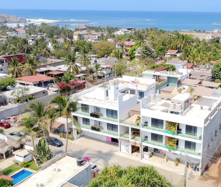 an aerial view of a white building with palm trees and the ocean at Punta Colibrí in Brisas de Zicatela