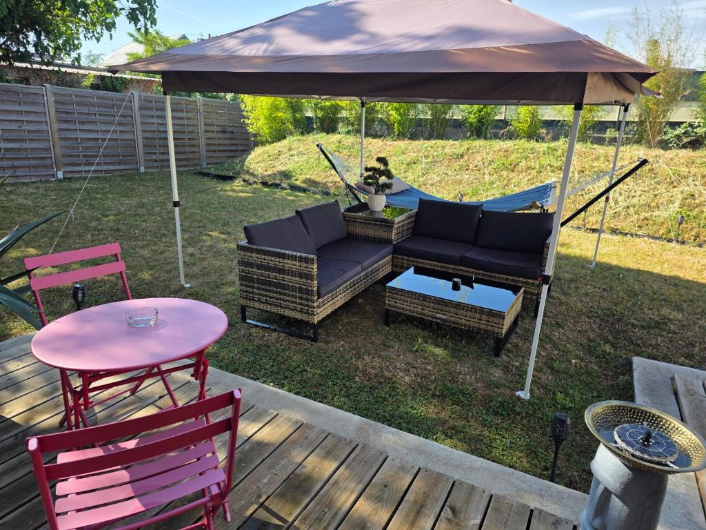 a patio with a table and an umbrella at Le Cercle de Victoria stationnement privé petit déjeuner compris in Bourges
