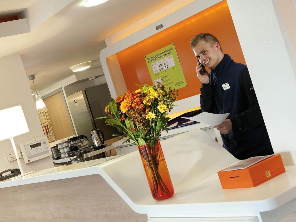 a man talking on a cell phone at a counter at Ibis Budget Rambouillet in Rambouillet