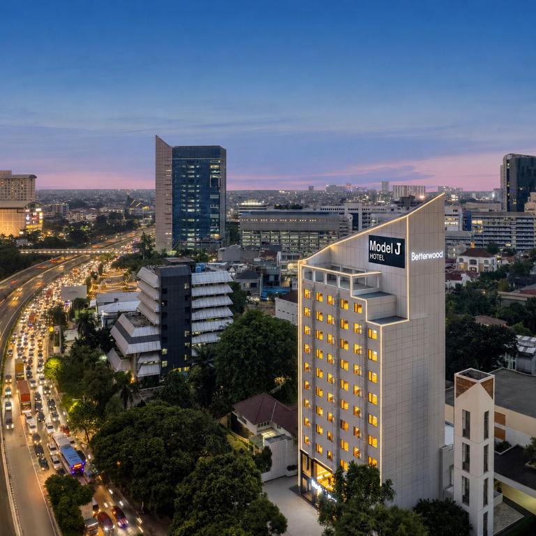 a tall building with a sign on it in a city at Model J Hotel Jakarta Central Park 曼居酒店 雅加达中央公园店 in Jakarta