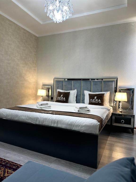 a bedroom with a large bed with a chandelier at Hotel Dera Bukhara in Bukhara