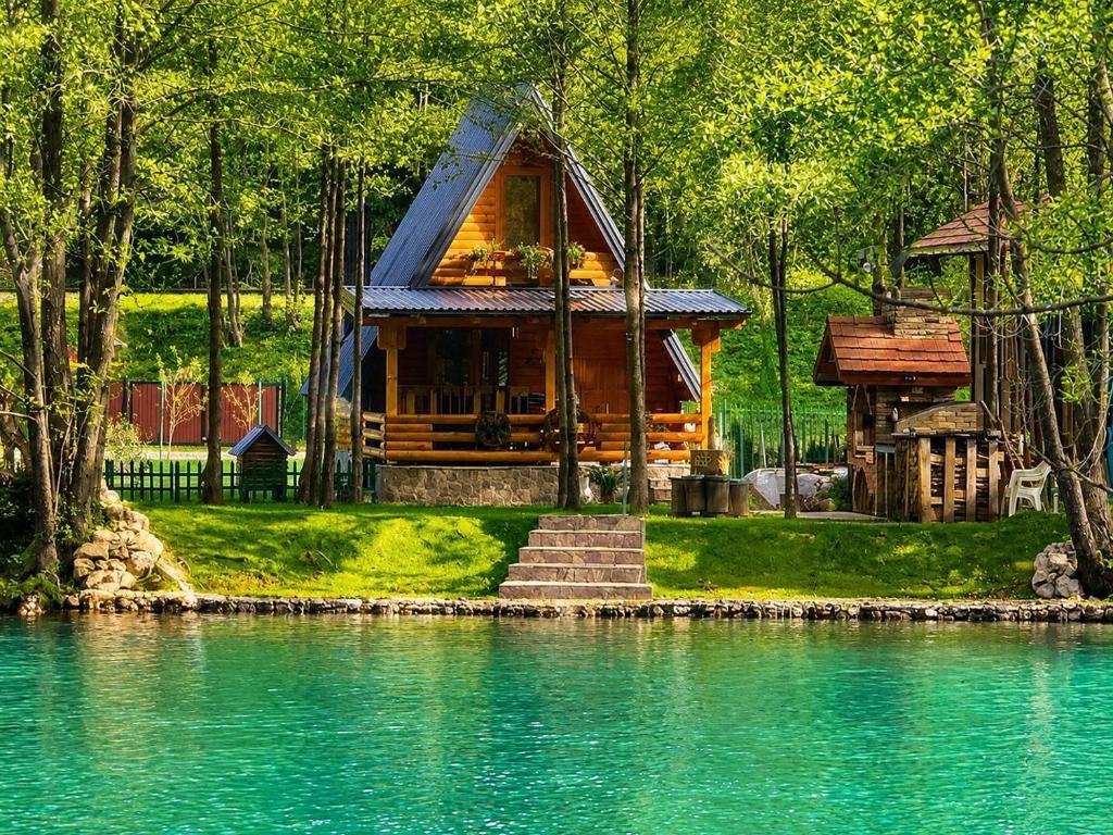 a cabin in the woods next to a body of water at Vikendica Raj in Bihać