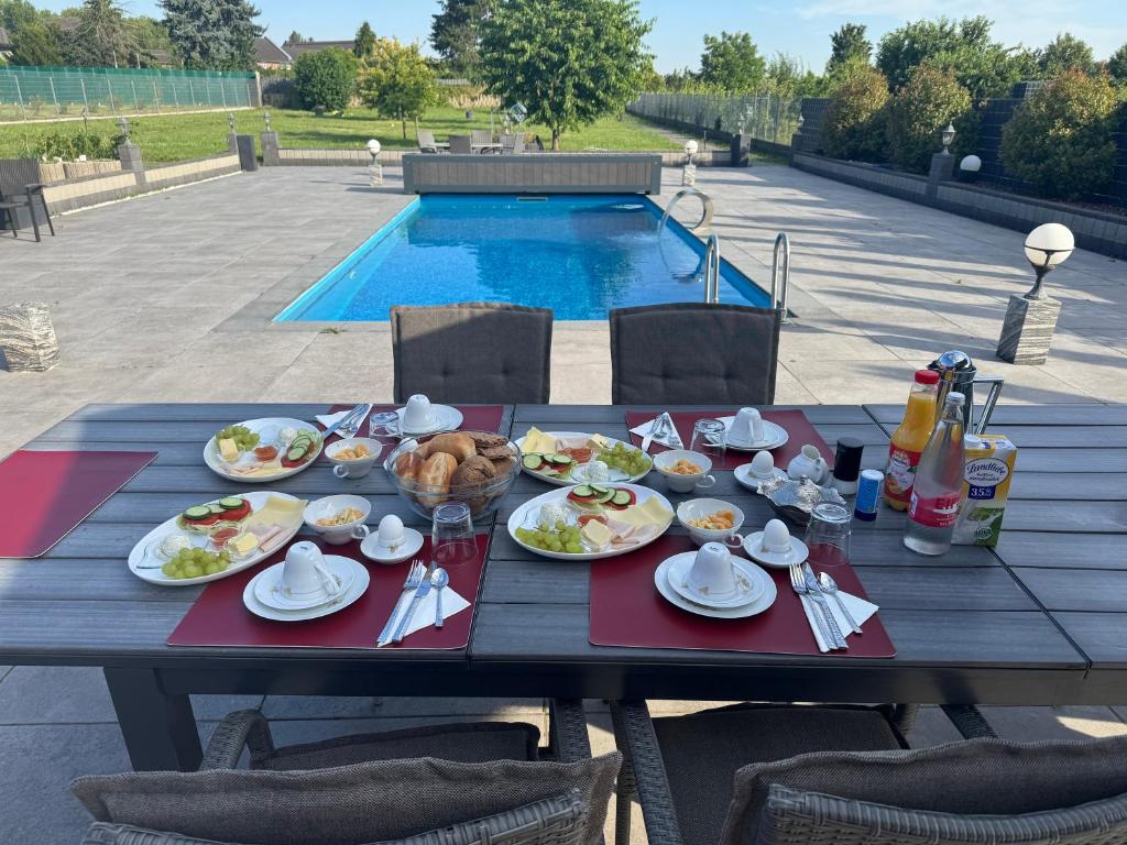 a table with plates of food on it next to a pool at Premium Apartment near Cologne in Hürth