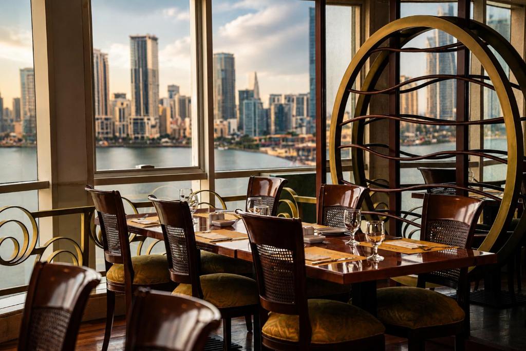 a dining room with a table and chairs and a window at Golden Tulip Sharjah in Sharjah