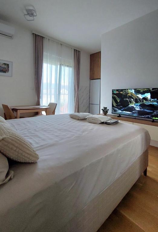 a bedroom with a large white bed with a flat screen tv at D&M Lux2 in Podgorica