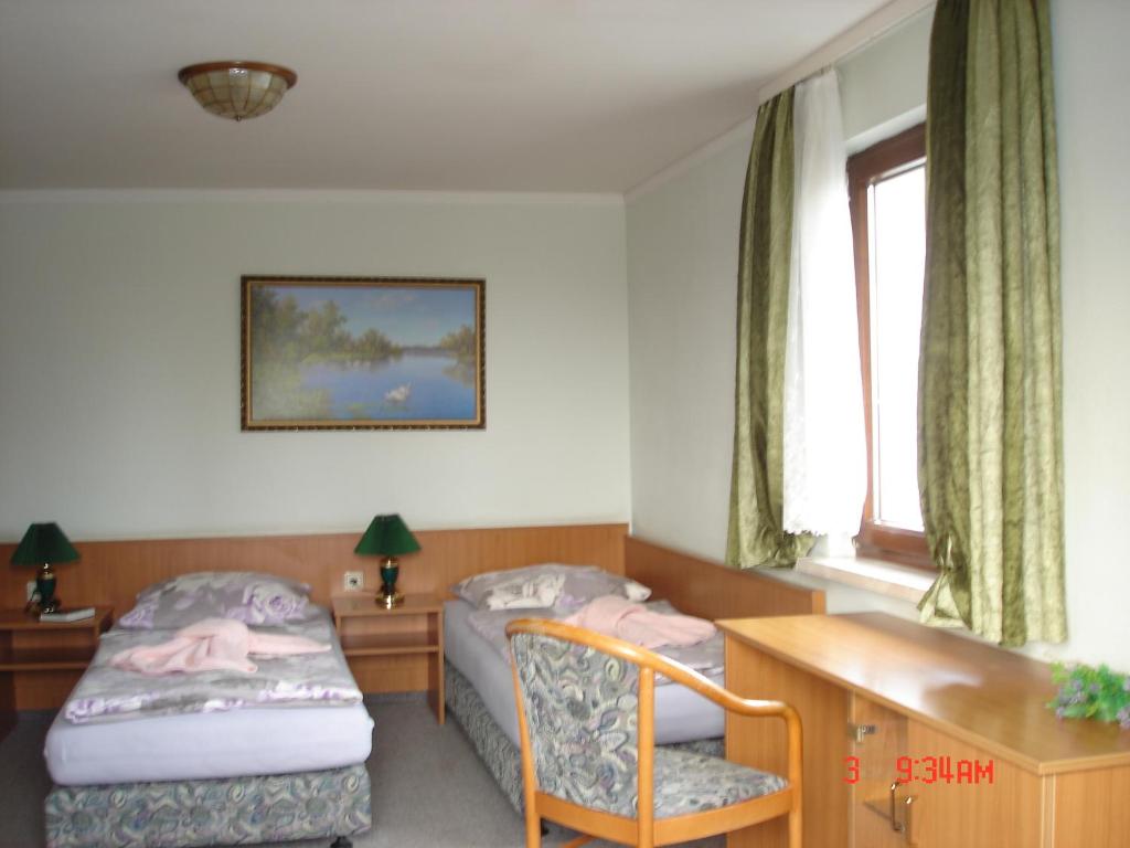 a bedroom with two beds and a desk and a window at Pension zum Schwanenteich in Haldensleben