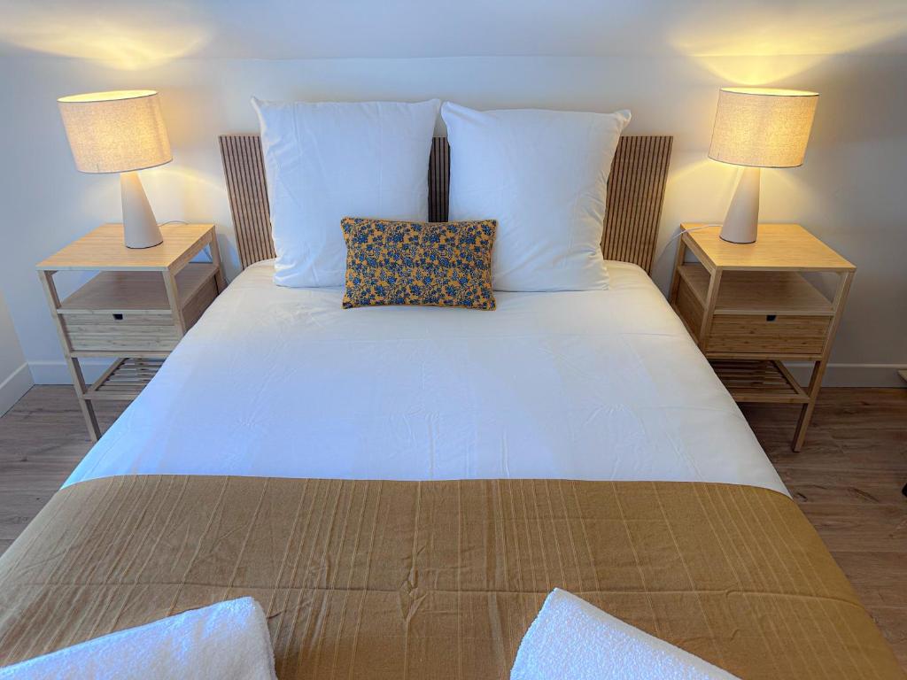 a large white bed with two nightstands and two lamps at Appartement Cosy avec parking à proximité de la Gare et de toutes les commodités in Orléans