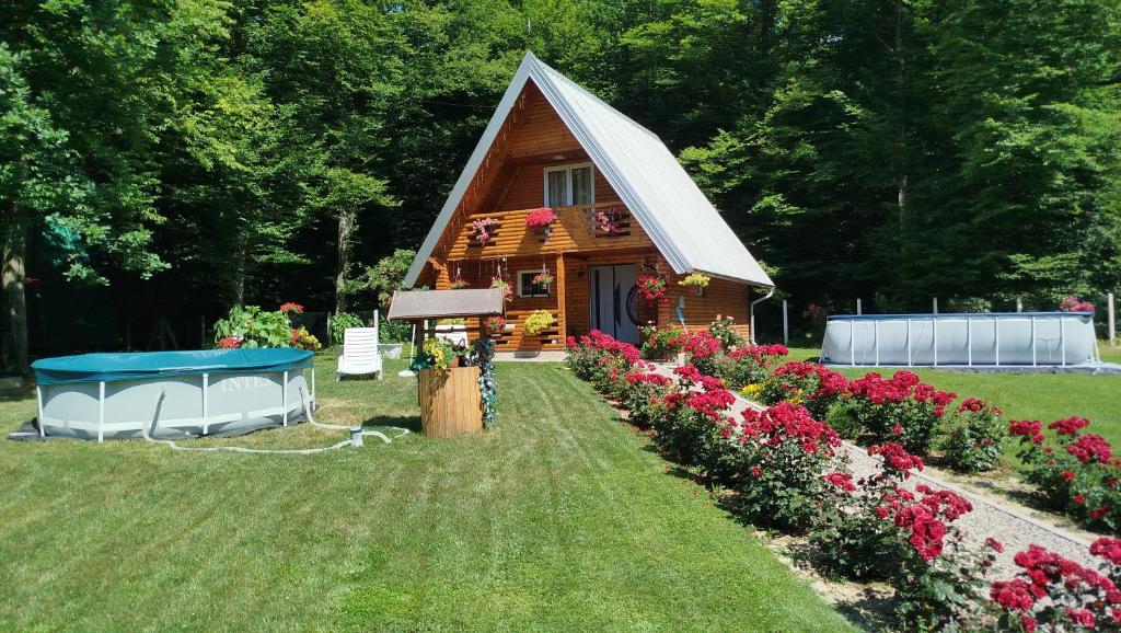 a cabin with a bunch of flowers in the yard at Vikendica Anastasija in Laktaši