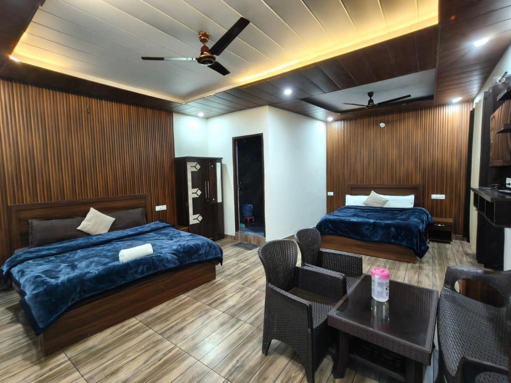 a hotel room with two beds and a table at HKS Orchards Stay in Kanatal