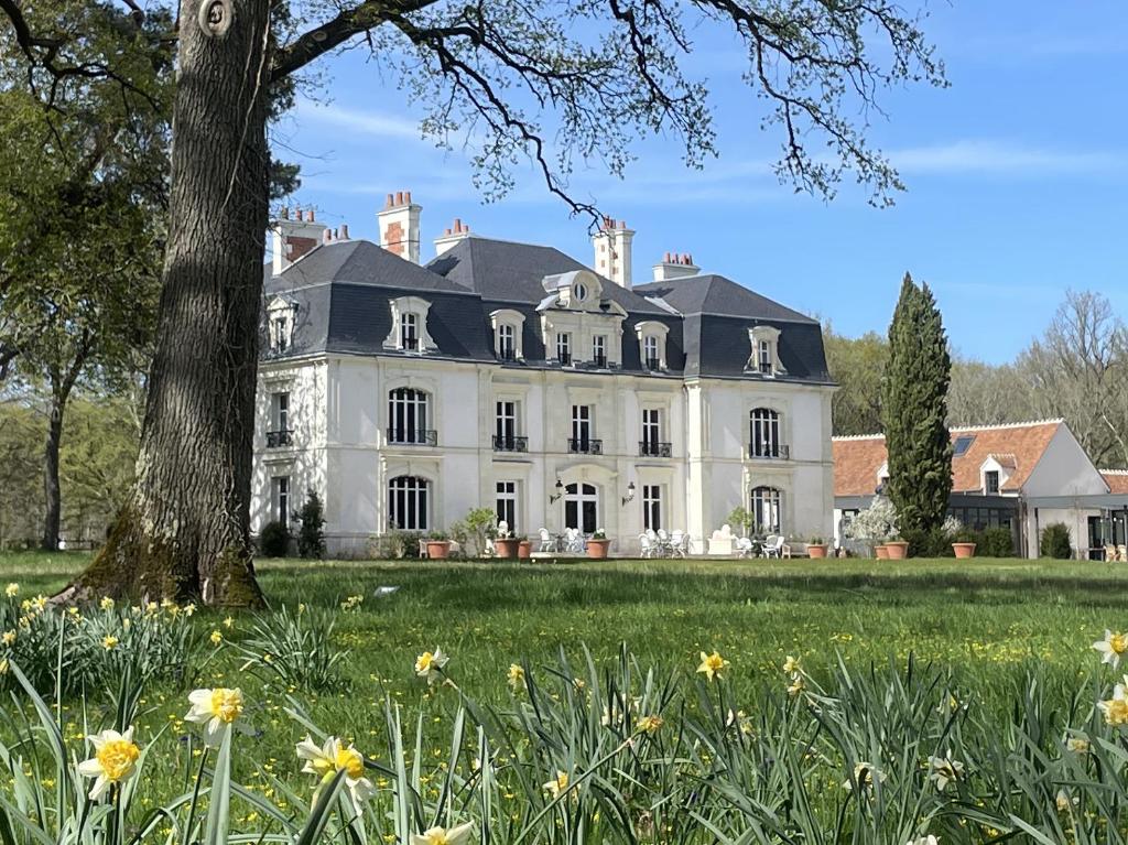 a large white house with a tree and flowers at Les Hayes en Sologne - Proche Chambord in Fontaines-en-Sologne