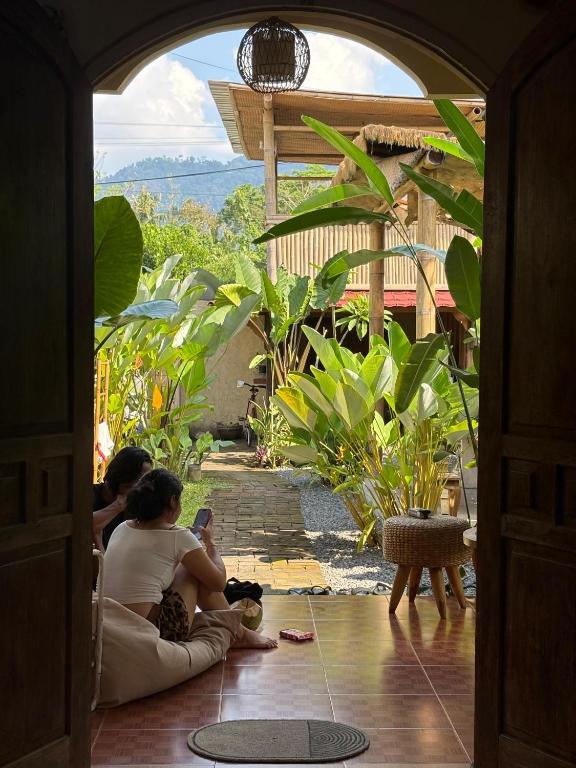 two people sitting on the floor in an open doorway at Social Ducks Hostel Borobudur in Borobudur