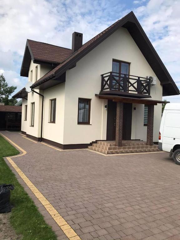 a white house with a van parked in the driveway at Lake House in Svityazʼ