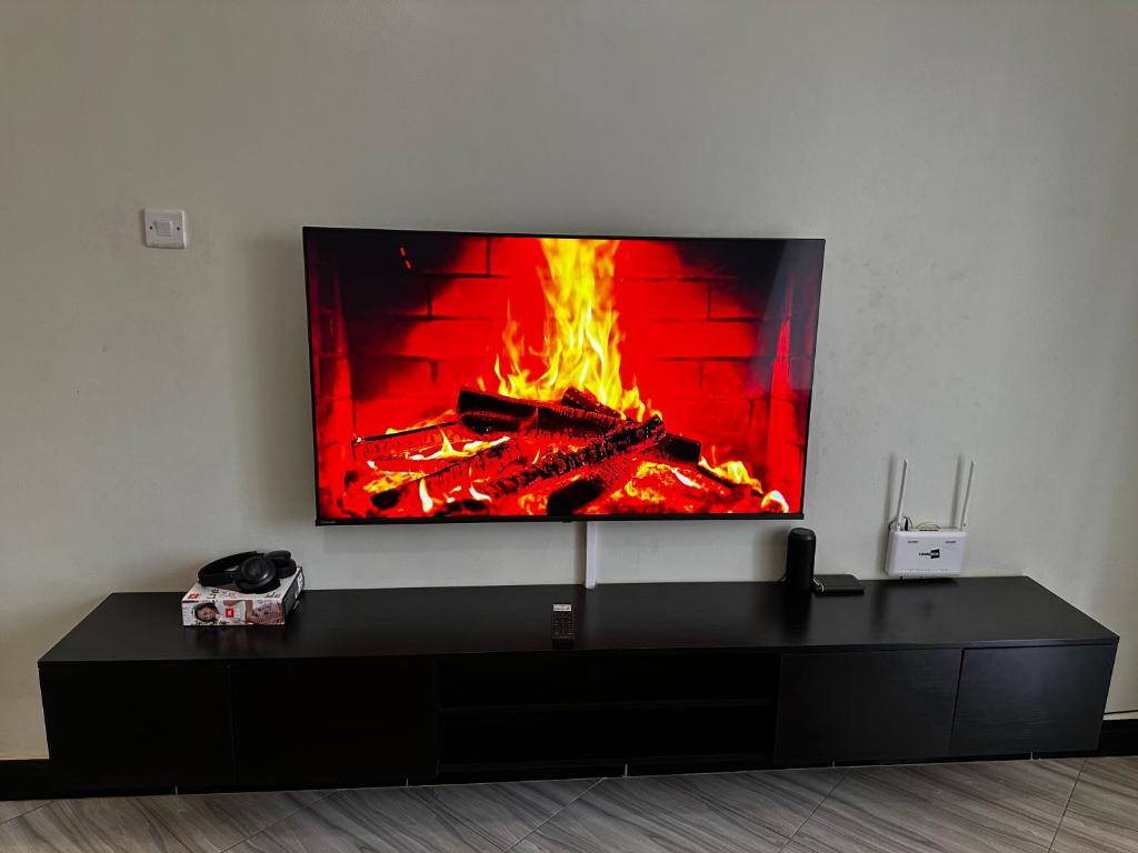 a tv on a wall with a fire in a fireplace at El SALI APARTMENTS in Buwate
