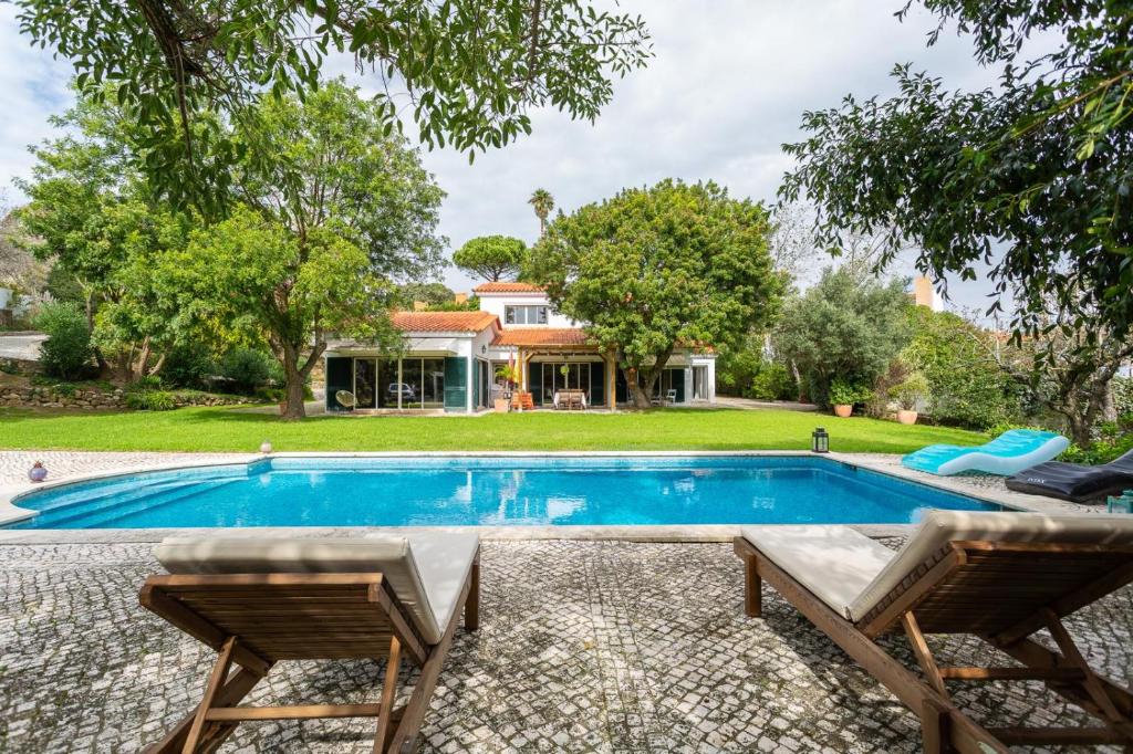 a swimming pool with two chairs and a house at Charming House in Cascais in Alcabideche