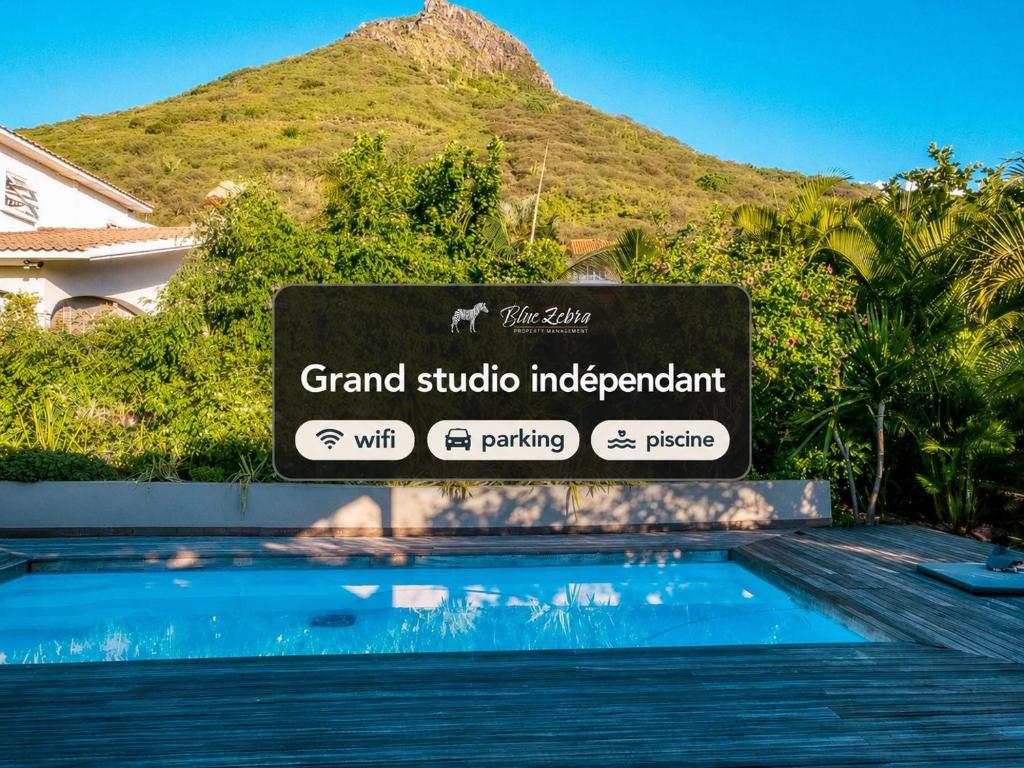 a sign in front of a swimming pool in front of a mountain at Blue Zebra - Le Jardin d'Antoinette in Rivière Noire