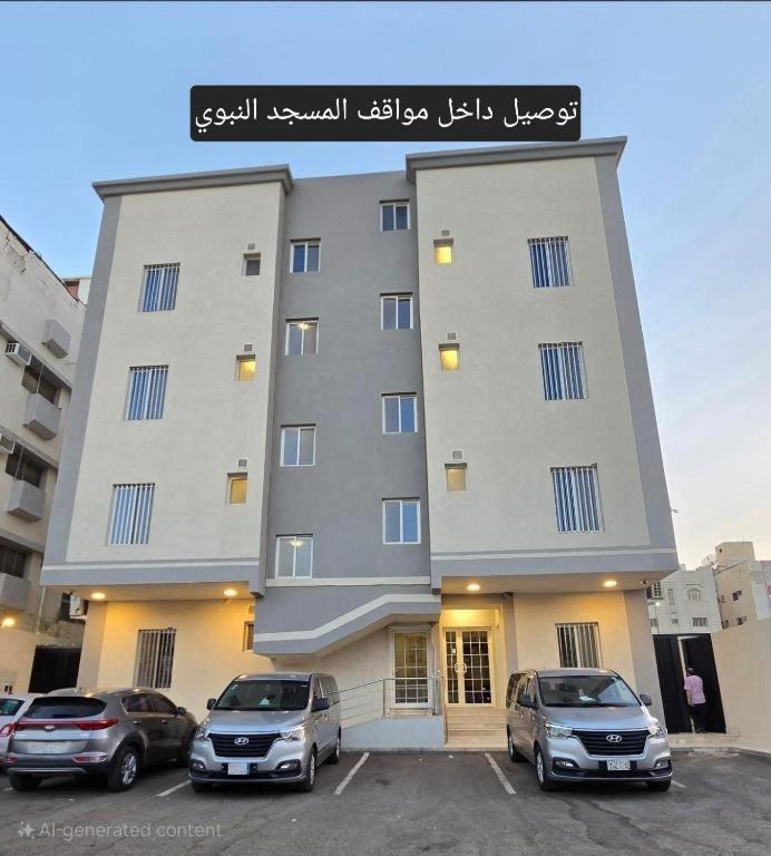 a large building with cars parked in a parking lot at شقق جادة قباء in Medina