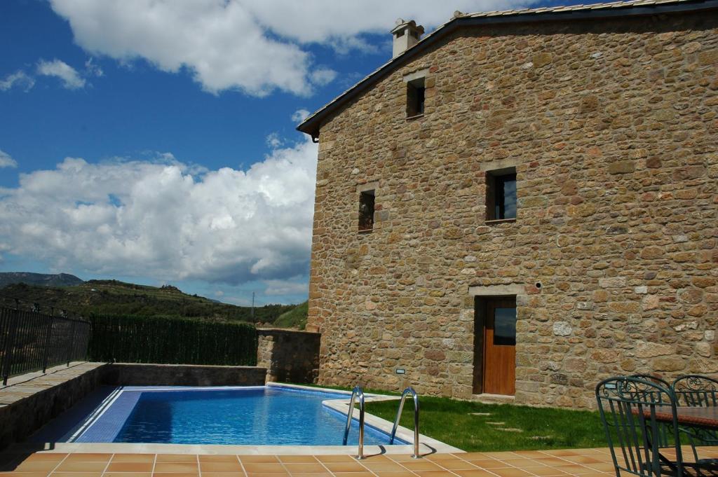 a swimming pool in front of a stone building at Cal Miger in Gualter
