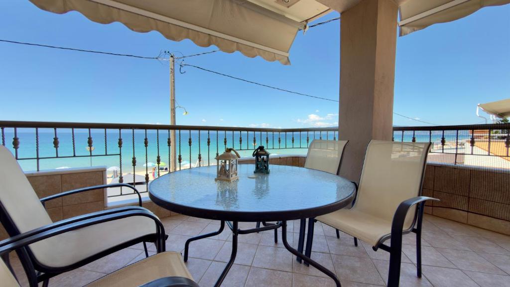 a table and chairs on a balcony with a view of the ocean at Remvi Beachfront Suites by Horizon Homes in Orfánion