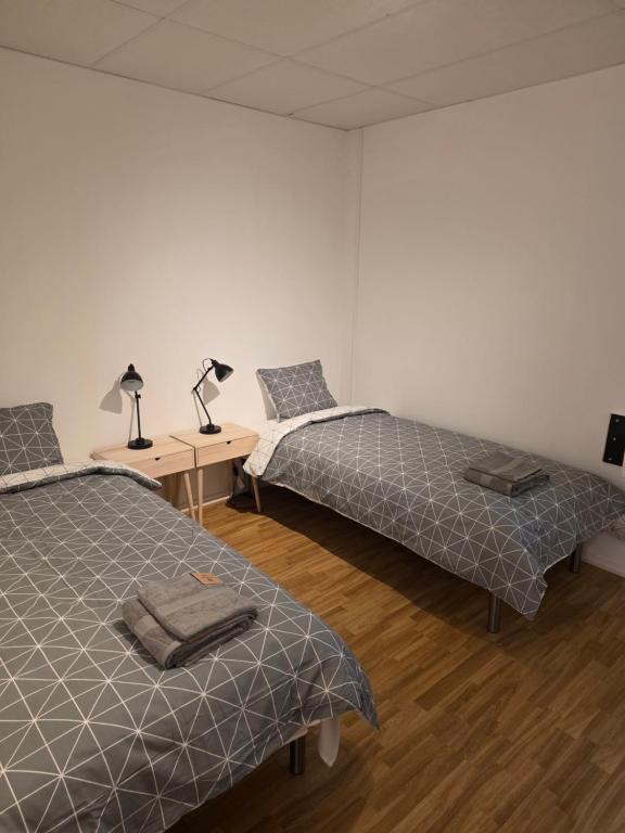 ein Zimmer mit zwei Betten und einem Schreibtisch mit zwei Lampen in der Unterkunft Örnsro Boende - Hus och rum in Skara
