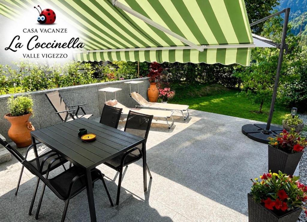 a black table and chairs under a green umbrella at La Coccinella vacation home in Druogno