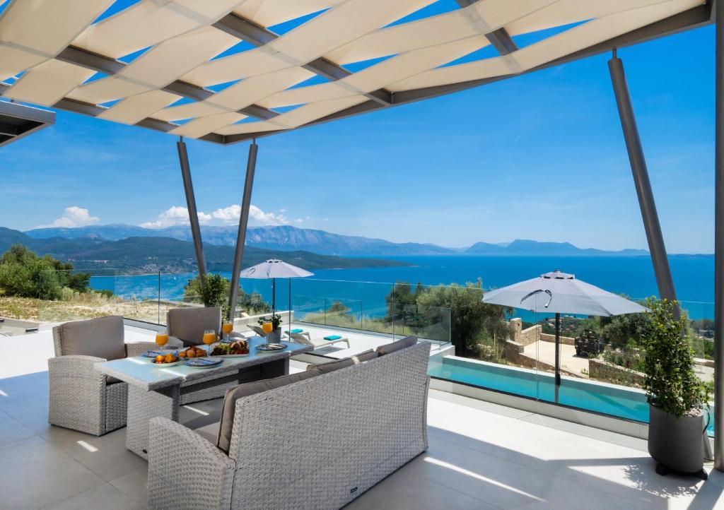 a patio with a table and chairs and a view of the water at Eleage Villas in Lefkada