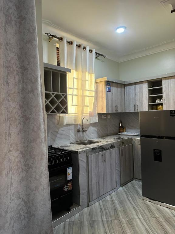 a kitchen with wooden cabinets and a black refrigerator at El SALI APPARENT,Najjera in Namugongo