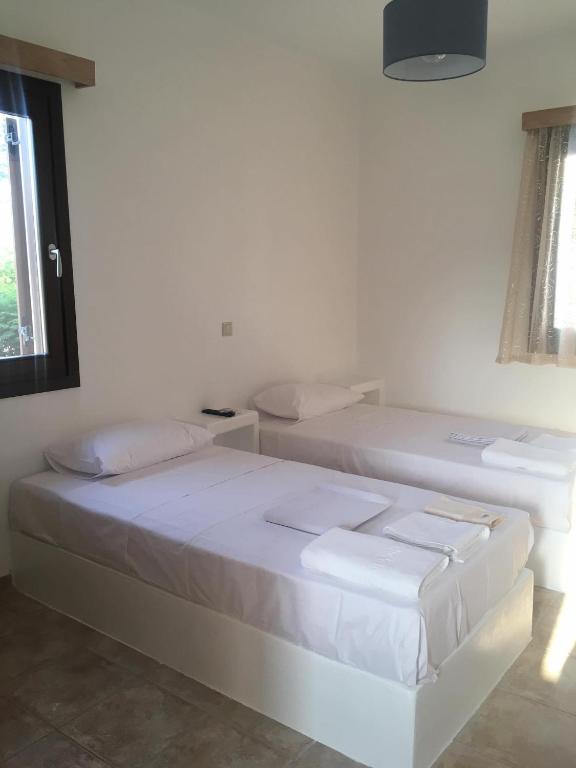 two beds in a white room with a window at Iliaxtida apartments II in Grámousa