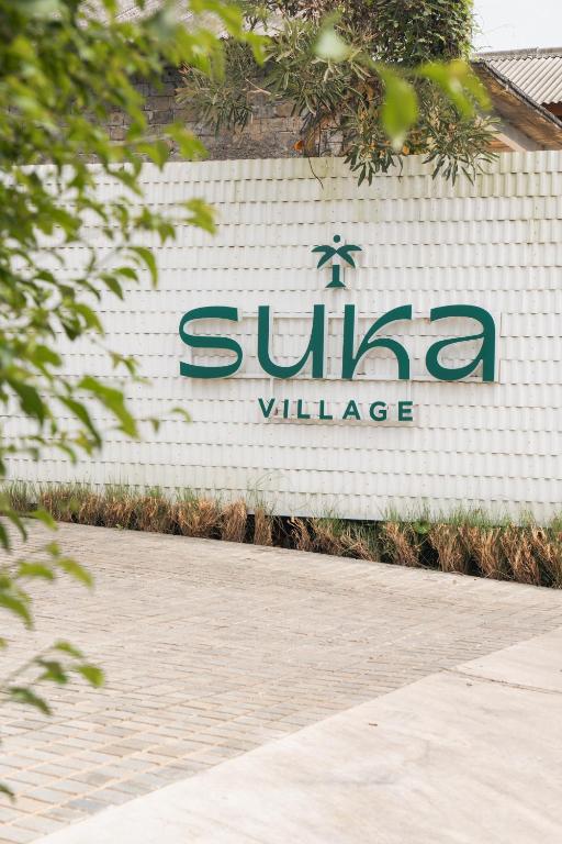 a sign for a villa village on the side of a building at Suka Village 