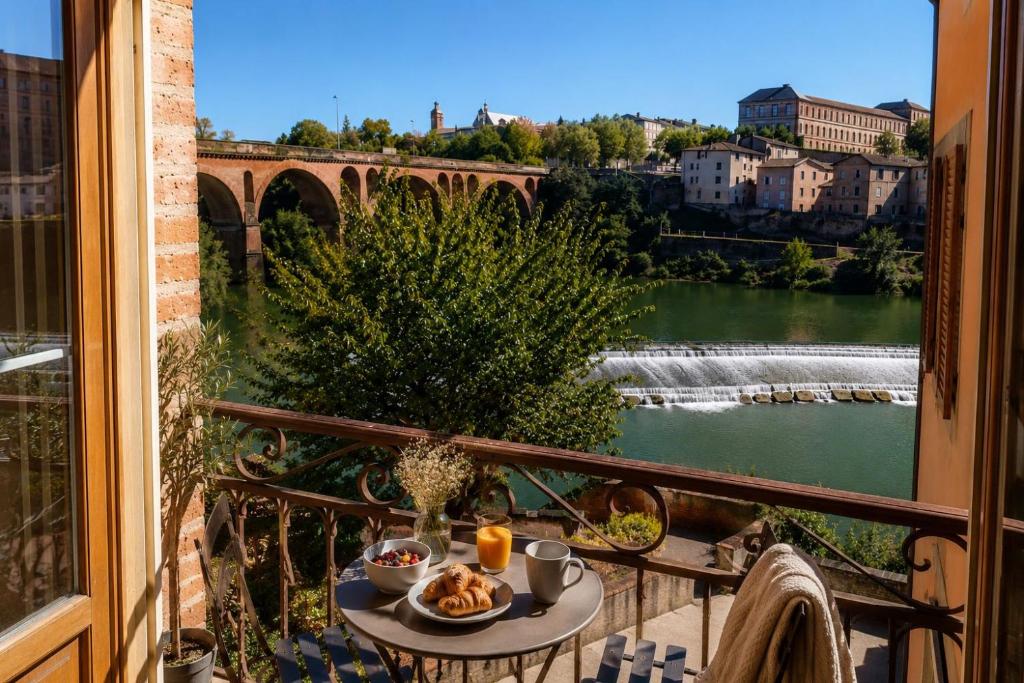 a table on a balcony with a view of a river at Au Fil de L eau in Albi